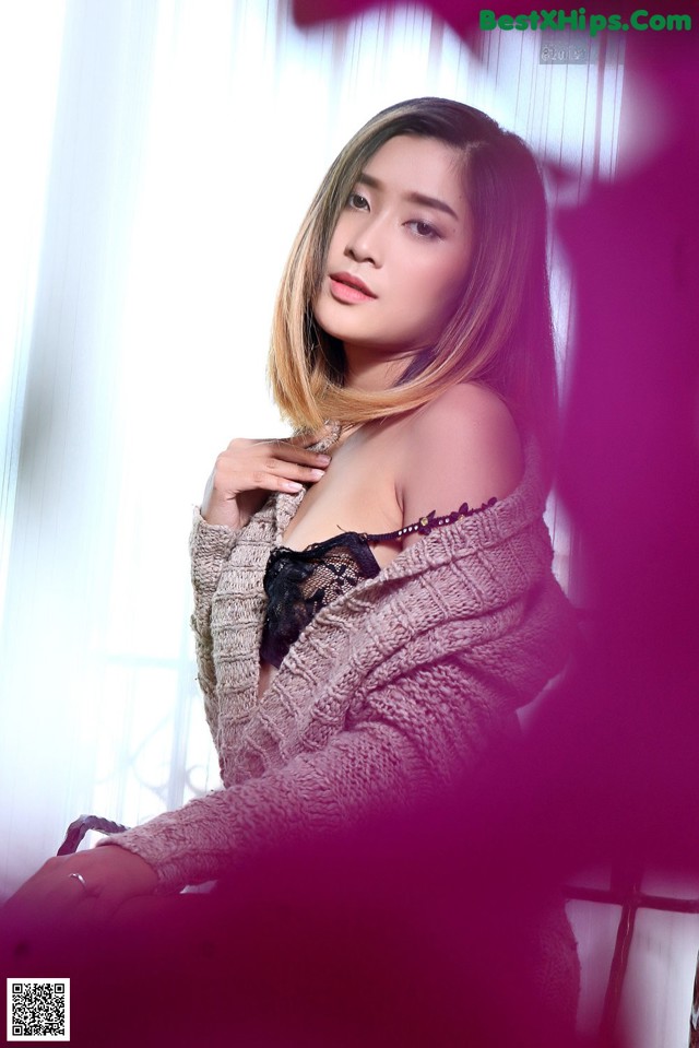 A woman in lingerie posing in front of a window.
